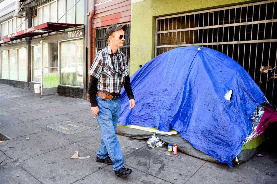 Man walking past tent on street