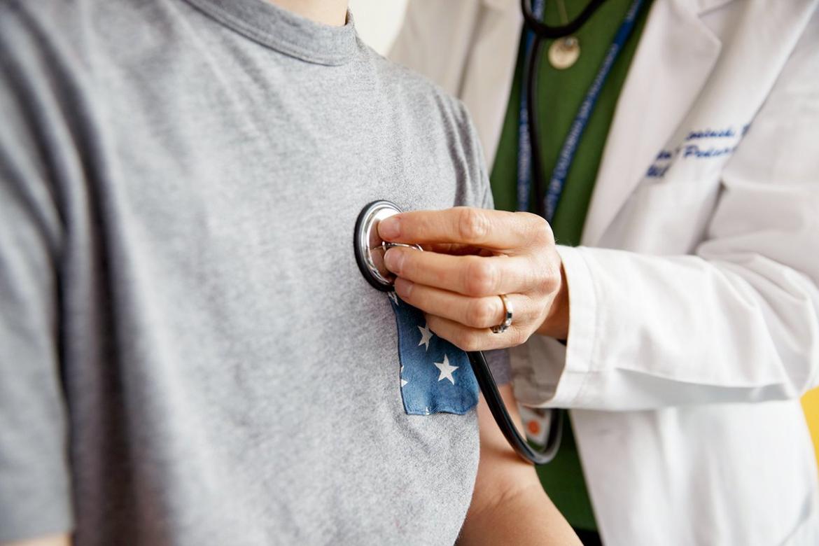 Doctor holding stethoscope on patient's chest