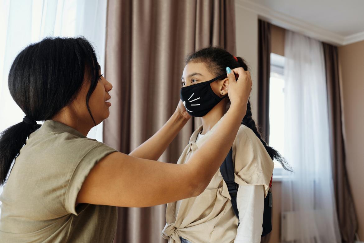 Adult helping a child put on a facial mask