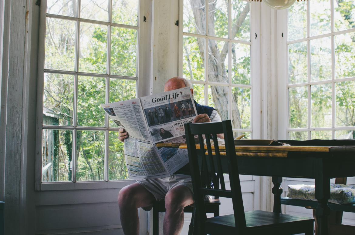 Seated older man reading a newspaper
