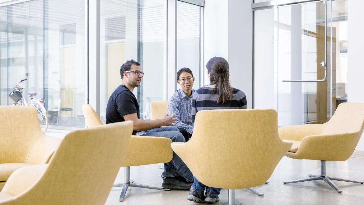 Three individuals conversing while seated around a small table