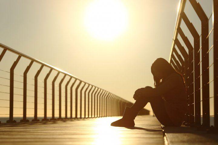 Silhouette of an adolescent sitting on a pedestrian bridge