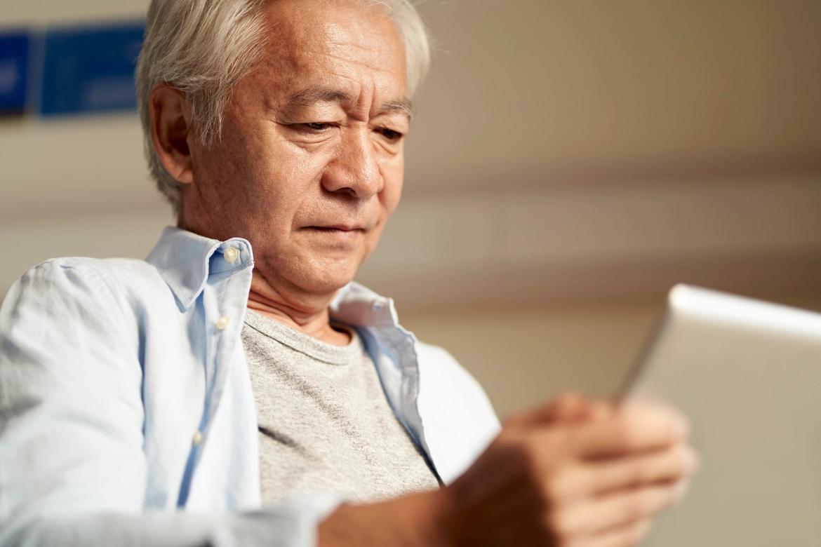Elderly man reading a tablet