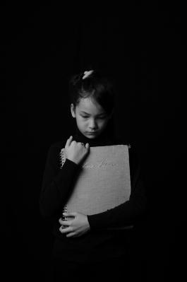 Black and white image of a girl holding a book