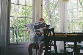 Person sitting a table while reading a newspaper