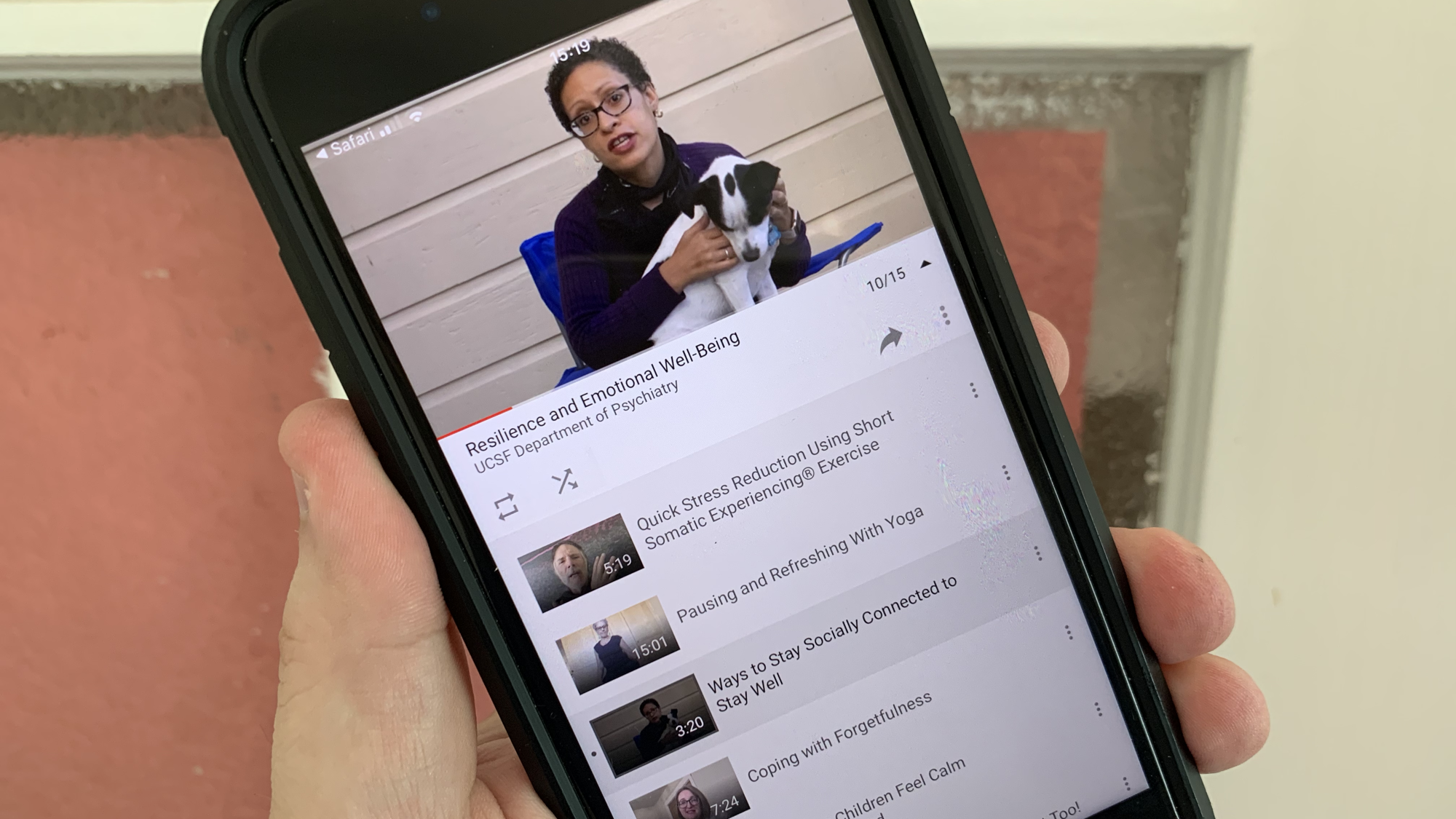 Hand holding an iPhone showing the video series on YouTube